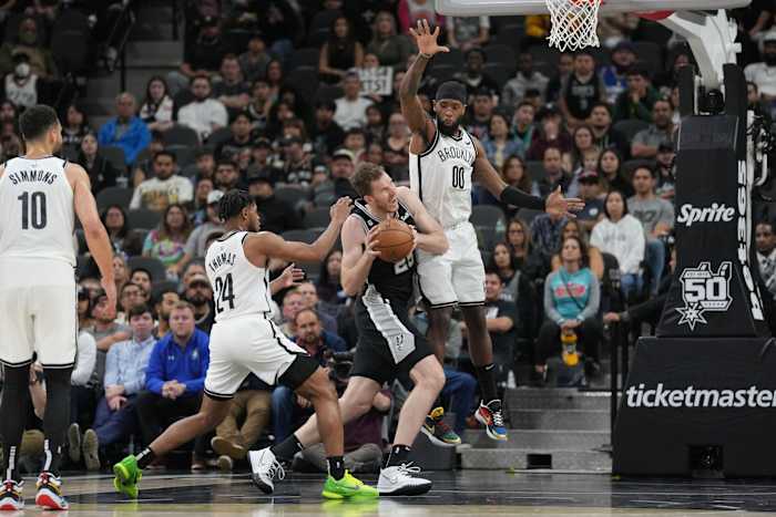 San Antonio Spurs center Jakob Poeltl (25) drives in between Brooklyn Nets guard Cam Thomas (24) and forward Royce O'Neale (00) in the second half at the AT&T Center